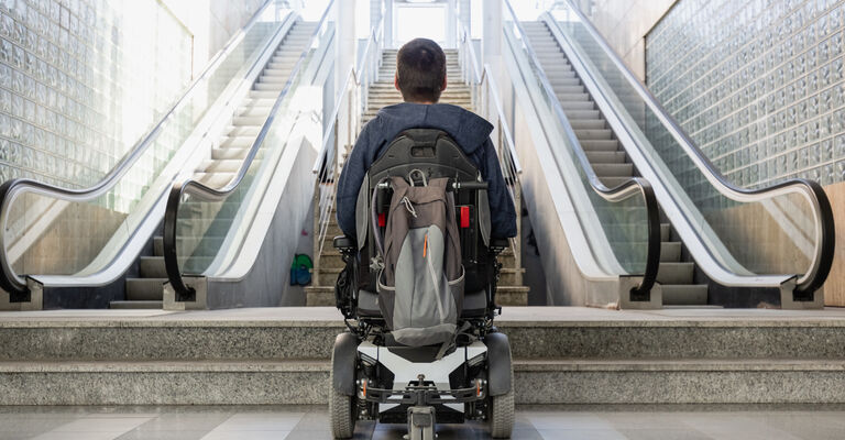 Man with disability on wheelchair stopped in front of staircase,