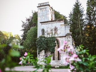 Park an der Ilm Eine majestätische Ruine mit kunstvollen Details, umgeben von einem friedlichen Wald, während bunte Blumen den Vordergrund schmücken.