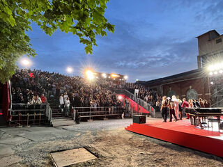 Sommertheater Eine große Menschenmenge applaudiert begeistert bei einer Abendveranstaltung unter einem bewölkten Himmel.