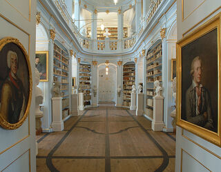 Anna Amalia Bibliothek Zwei Porträts in goldenen Rahmen hängen an den Wänden, während das Licht sanft durch den Raum strömt.