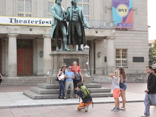Die Statue von Goethe und Schiller wird von einer Gruppe junger Leute umgeben, die sich für ein Erinnerungsfoto versammeln.
