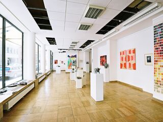 Moderne Kunstgalerie mit vielfältigen Kunstwerken und Skulpturen Ein heller Ausstellungsraum mit weißen Wänden, in dem verschiedene Kunstwerke und Skulpturen auf Podesten präsentiert werden.
