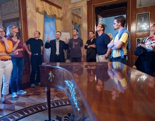 Lange Nacht der Museen Eine Gruppe von Menschen hört aufmerksam einem Vortrag in einem eleganten Raum mit historischen Details zu.