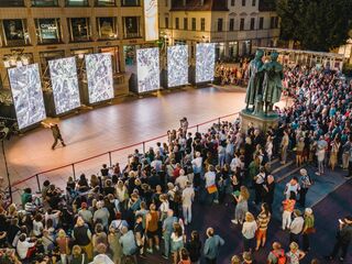 Kunstfest Weimar, Eroeffnung Eine große Menschenmenge versammelt sich auf dem Theaterplatz, während ein Tänzer vor mehreren großen Bildschirmen zur Eroeffnung des Kunstfestsauftritt.