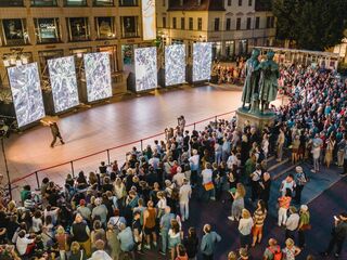 Kunstfest Weimar, Eroeffnung Eine große Menschenmenge versammelt sich auf dem Theaterplatz, während ein Tänzer vor mehreren großen Bildschirmen zur Eroeffnung des Kunstfestsauftritt.