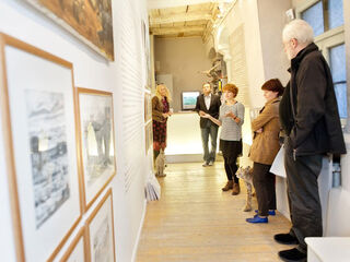 ACC Galerie Eine Gruppe von fünf Personen steht in einem hellen Raum in der Galerie ACC, umgeben von gerahmten Bildern an der Wand.
