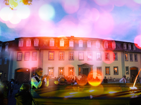 Eine lebhafte Szene auf dem Frauenplan Weimar mit Menschen, die an einem Brunnen stehen, während die Dämmerung über dem Goethe Wohnhaus hereinbricht.