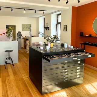 Stadtelster Ein stilvoller Verkaufsbereich mit zwei schwarzen Barhockern und einem großen Tisch voller Schmuck und Accessoires.