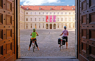 Stadtschloss Zwei Radfahrer stehen vor einer beeindruckenden historischen Architektur und genießen den Blick auf den Innenhof.