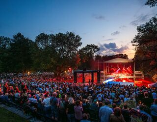Eine große Menschenmenge versammelt sich beim Meute-Konzert im Weimarhallenpark, während die Sonne hinter den Bäumen untergeht.