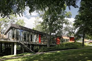 Moderne Architektur umgeben von üppigem Grün und Bäumen Ein modernes, freistehendes Gebäude mit großen Fenstern, umgeben von üppigem Grün und Bäumen, strahlt Ruhe aus.