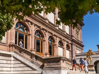 Museum Neues Weimar, Foto: Thomas Müller, weimar GmbH Ein goldener Menschenskulptur steht stolz neben dem Eingang, während Besucher das kulturelle Zentrum betreten.