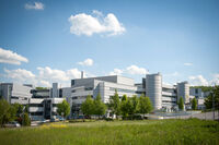 Aufnahme des Weimarer Klinikums aus der Ferne, im Vordergrund Wiese, blauer Himmel mit einigen weißen Wolken