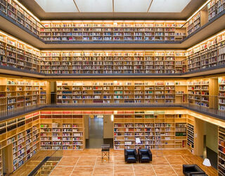 Anna Amalia Bibliothek Eine moderne Bibliothek mit mehreren Etagen, die von warmem Licht erhellt wird und voll mit Bücherregalen ist.