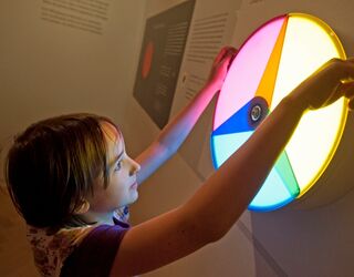 Lange Nacht der Museen In einem Museum untersucht ein Kind einen farbigen, interaktiven Lichtkreis und zeigt begeistert darauf.