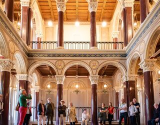 Führung durch die Schlosskapelle im Stadtschloss Eine Gruppe von Menschen steht in einem prächtigen Raum mit hohen Säulen und kunstvollen Deckenverzierungen.