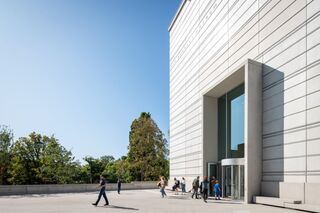 Bauhaus Museum Weimar Im Vordergrund sind Menschen zu sehen, die in ein Museum eintreten, während die Architektur des Gebäudes im Hintergrund dominiert.