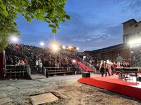 Eine große Menschenmenge versammelt sich auf der Freiluftbühne auf dem e-werk-Gelände, während die Dämmerung einsetzt und die Lichter leuchten.