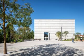 Bauhaus Museum Weimar Ein modernes, minimalistisches Gebäude mit einer glatten Fassade steht im Mittelpunkt, umgeben von Bäumen und Besuchern.